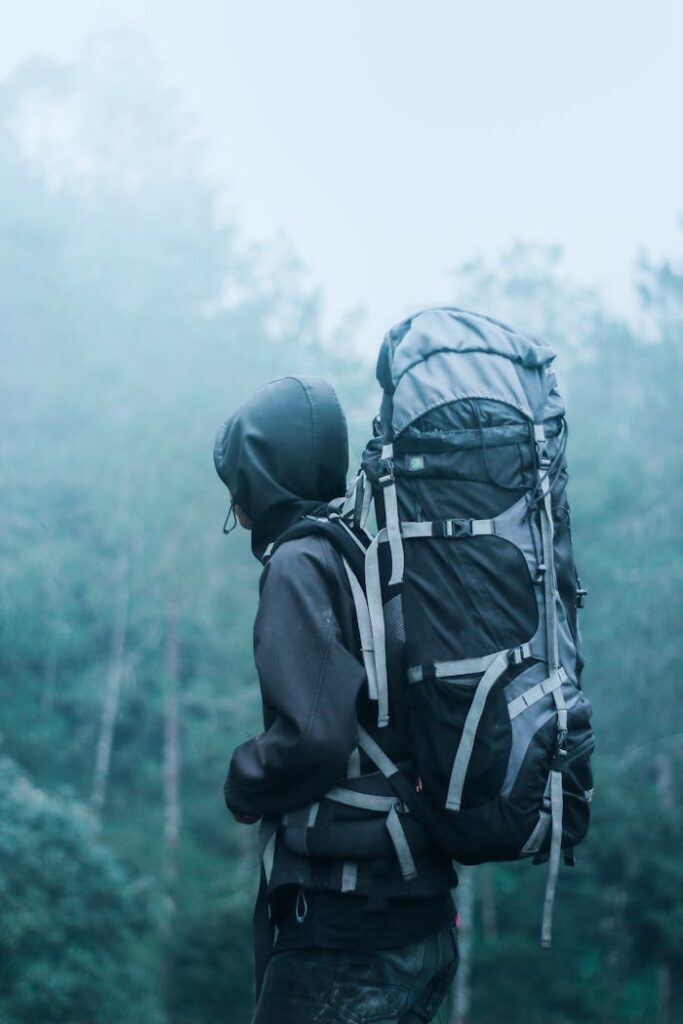 Solo hiker with large backpack in a misty forest, exploring nature's serene beauty.
